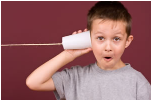 Boy holding cup to ear listening like a telephone